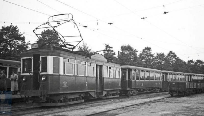 De overige lijnen van de NBM kenden allemaal smalspoor (1067mm). Van Zeist liepen lijnen naar Driebergen, Arnhem en Amersfoort terwijl vanuit Doorn ook Wijk bij Duurstede kon worden bereikt. Op deze foto staat de 77 met drie aanhang­wagens van de serie 30-54 in Amersfoort. De motor­wagen werd door Werkspoor gebouwd in 1924 en de aanhang­wagens zijn van Allan, daterend uit 1910, maar alle vier dus van Nederlands fabricaat. De bestuurder kon via de deur in de kop zijn plaats bereiken. Aan de overzijde van het perron staat een andere tram gereed en op het zijspoor zien we nog aan aantal goederenwagens. De foto werd op 17 mei 1937 genomen door H.G.Hesselink. (NVBS-fotonummer 170.736)
